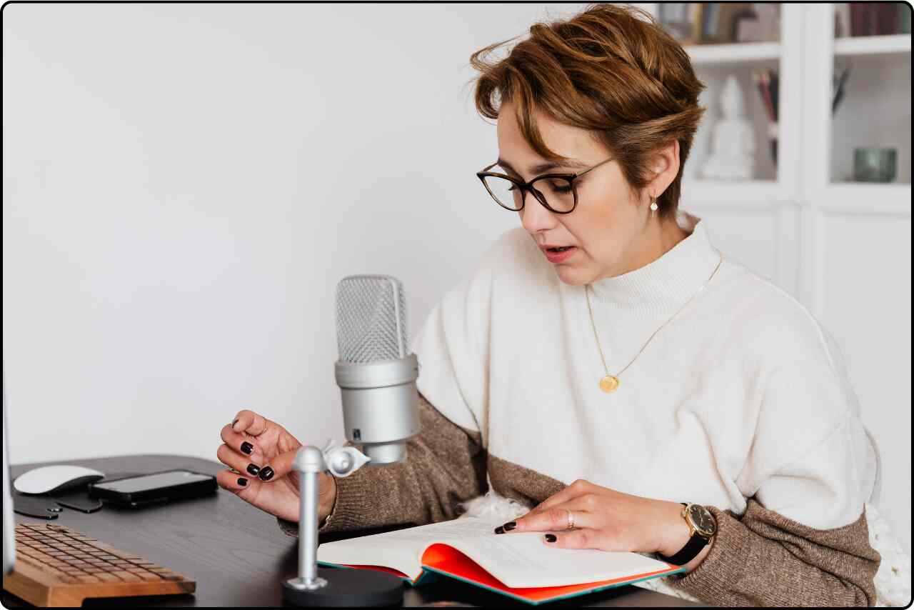 Woman narrating a story into a microphone while recording an audiobook.